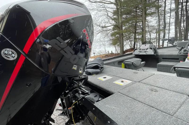 Slide: The Image of 2026 Lund 2075 Pro-V Bass XS boat with powerful engine, docked near trees. - 12