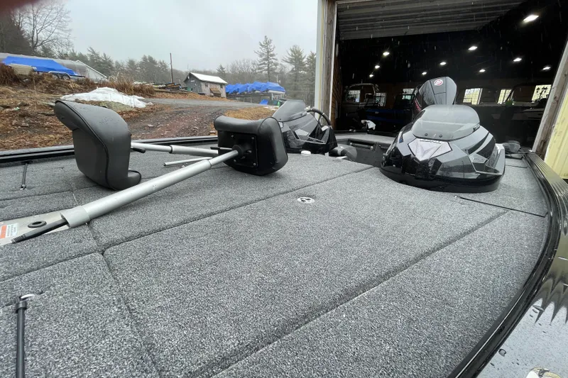 Slide: The Image of 2026 Lund 2075 Pro-V Bass XS boat with spacious deck and seating in a garage setting. - 9