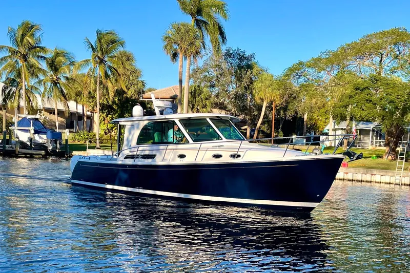 Slide: The Image of 2023 Back Cove 39O boat cruising on a sunny day with palm trees in the background. - 53