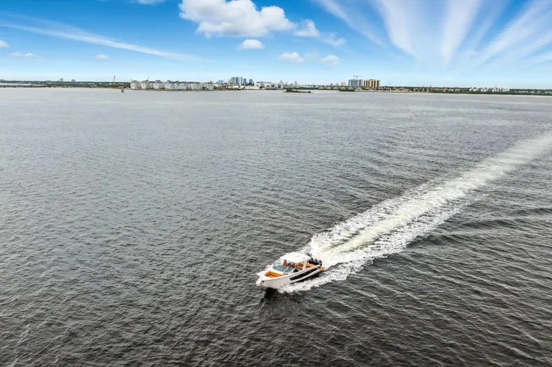 Slide: The Image of Aviara AV36 OB 2021 boat cruising on open water with city skyline in background. - 7