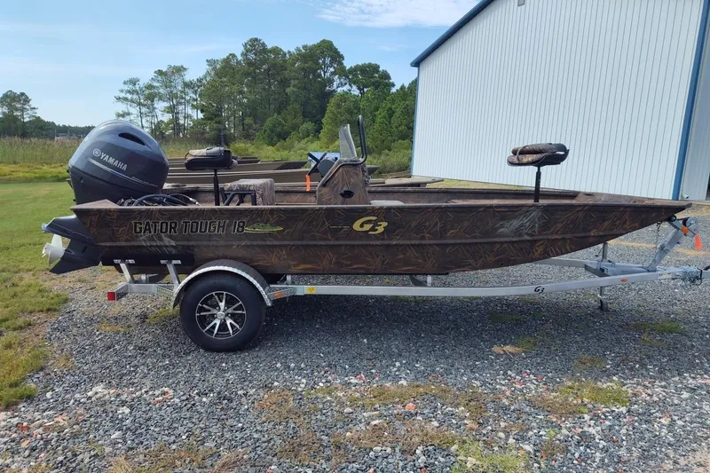 The Image of 2025 G3 Gator Tough 18 CC boat on trailer, outdoors with Yamaha motor. - 0
