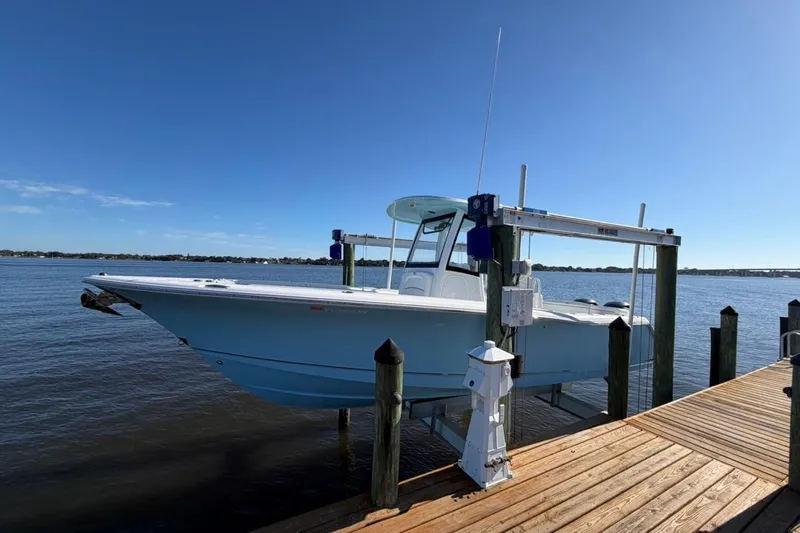 The Image of 2019 Sea Hunt Ultra 275 SE boat on lift by wooden dock, under clear blue sky. - 1