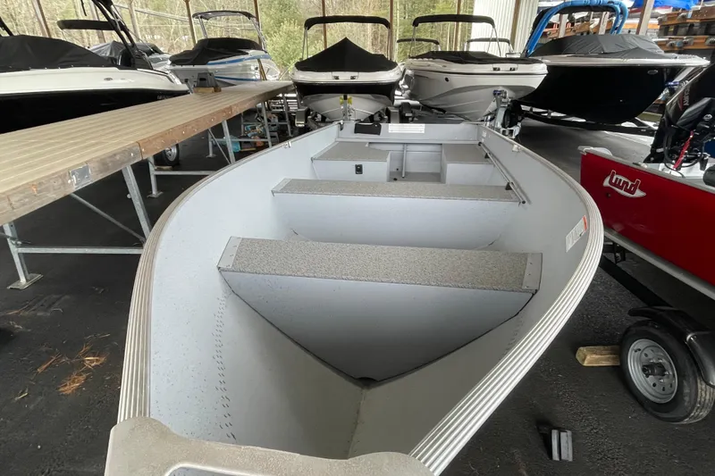 Slide: The Image of 2026 Lund WC-14 boat in storage, surrounded by other boats, showcasing interior seating. - 20