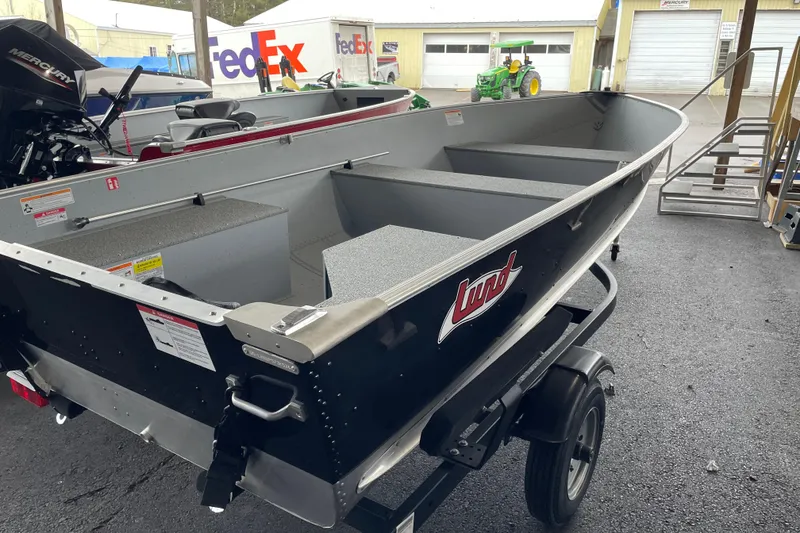 Slide: The Image of 2026 Lund WC-14 boat on trailer, displayed outdoors near FedEx trucks. - 8