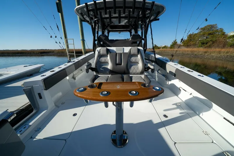 Slide: The Image of 2024 Freeman 38 boat interior with luxury seating and wooden table on calm water. - 34