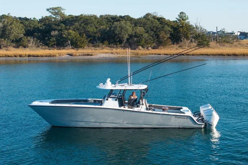 Slide: The Image of 2024 Freeman 38 boat on calm water, surrounded by lush greenery. - 5