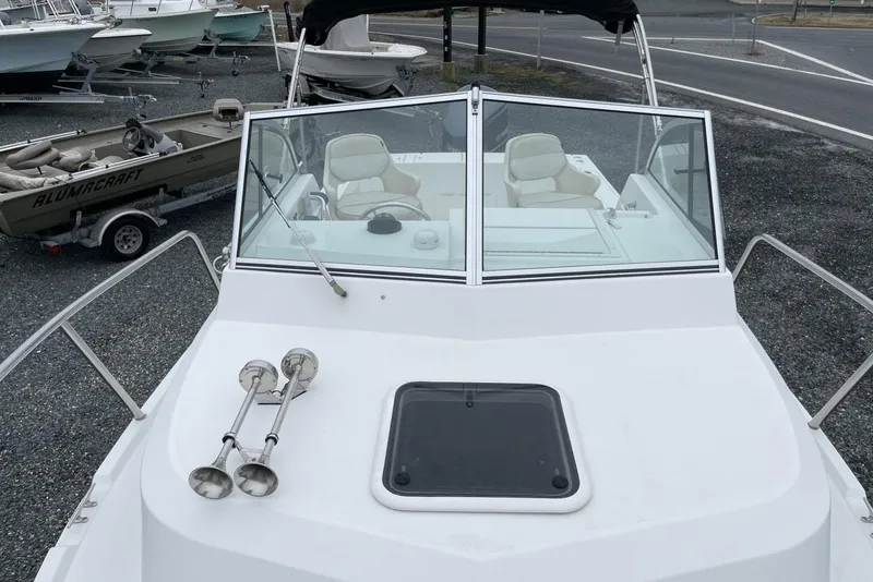 Slide: The Image of 2014 Parker 2310 DV Walkaround boat with windshield and seating, parked on gravel. - 12