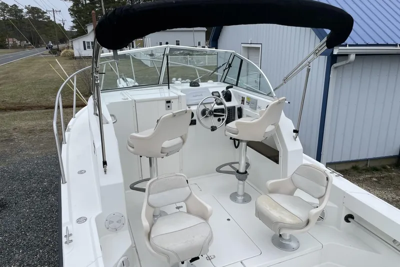 Slide: The Image of 2014 Parker 2310 DV Walkaround boat with seating and steering wheel, docked outdoors. - 7