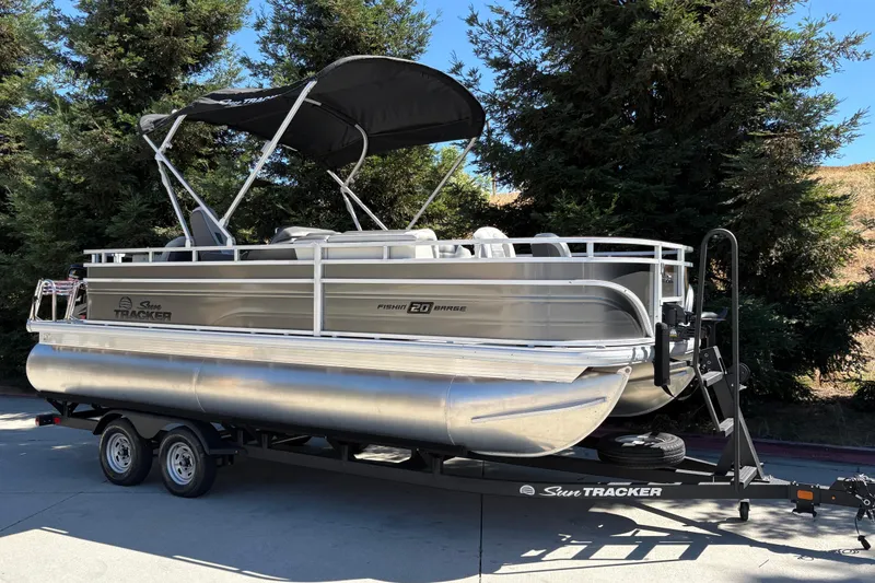 Slide: The Image of 2026 Sun Tracker Fishin' Barge 20 DLX pontoon boat on trailer, parked outdoors. - 4