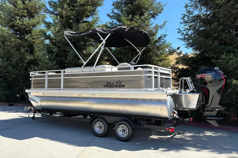 Slide: The Image of 2026 Sun Tracker Fishin' Barge 20 DLX pontoon boat with canopy, parked outdoors. - 8