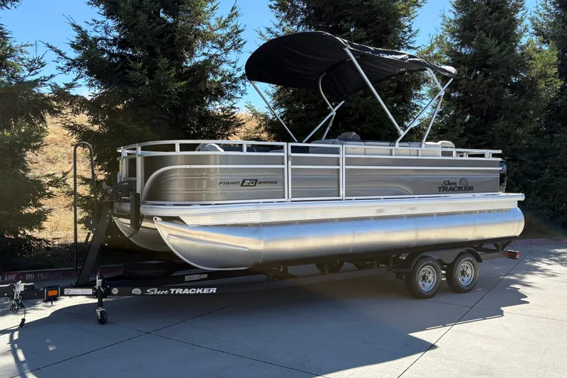 Slide: The Image of 2026 Sun Tracker Fishin' Barge 20 DLX pontoon boat on trailer, parked outdoors. - 3