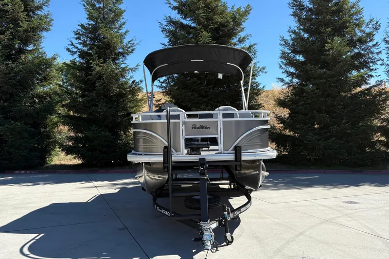 Slide: The Image of 2026 Sun Tracker Fishin' Barge 20 DLX pontoon boat on trailer, surrounded by trees. - 12
