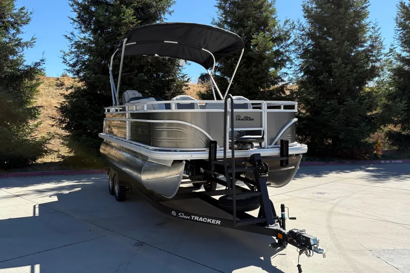 Slide: The Image of 2026 Sun Tracker Fishin' Barge 20 DLX pontoon boat on trailer, parked outdoors. - 5