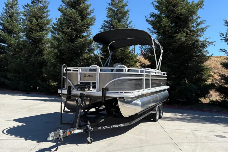 Slide: The Image of 2026 Sun Tracker Fishin' Barge 20 DLX pontoon boat on trailer, parked outdoors. - 6