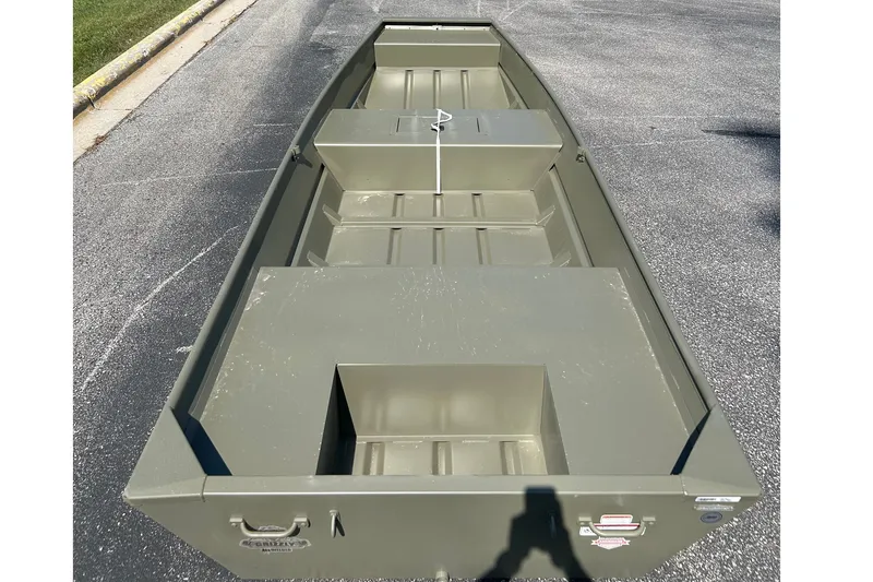 Slide: The Image of 2026 Tracker Grizzly 15 Jon boat on pavement, showcasing interior seating and storage. - 2