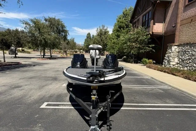 Slide: The Image of 2026 Nitro Z17 boat parked in a sunny lot, surrounded by trees and buildings. - 2
