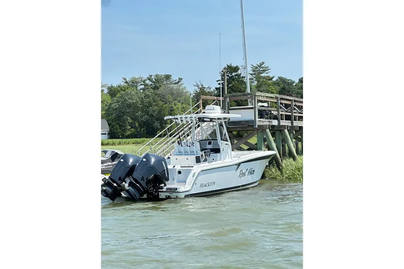 The Image of 2022 Blackfin 252 CC boat docked by wooden pier, featuring dual outboard motors. - 0