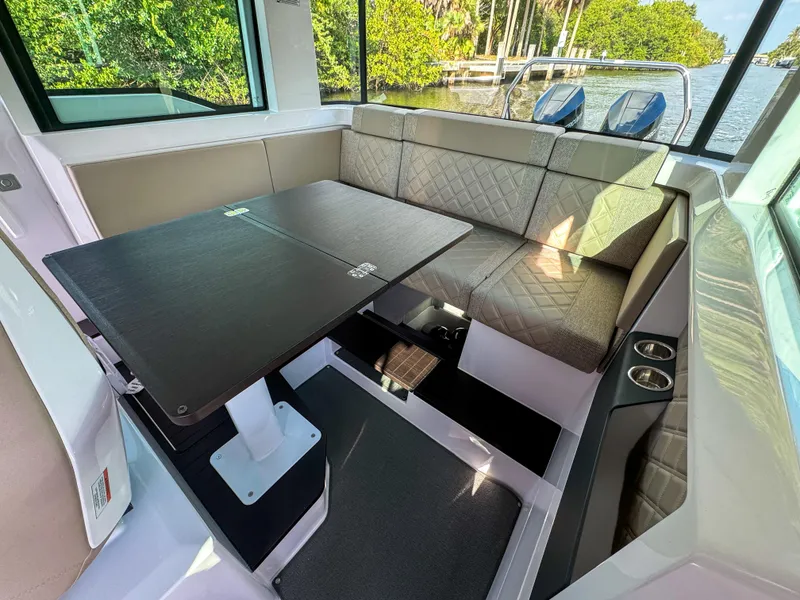 Slide: The Image of 2024 Axopar 37XC CROSS CABIN interior with seating and table, featuring modern design and waterfront view. - 15