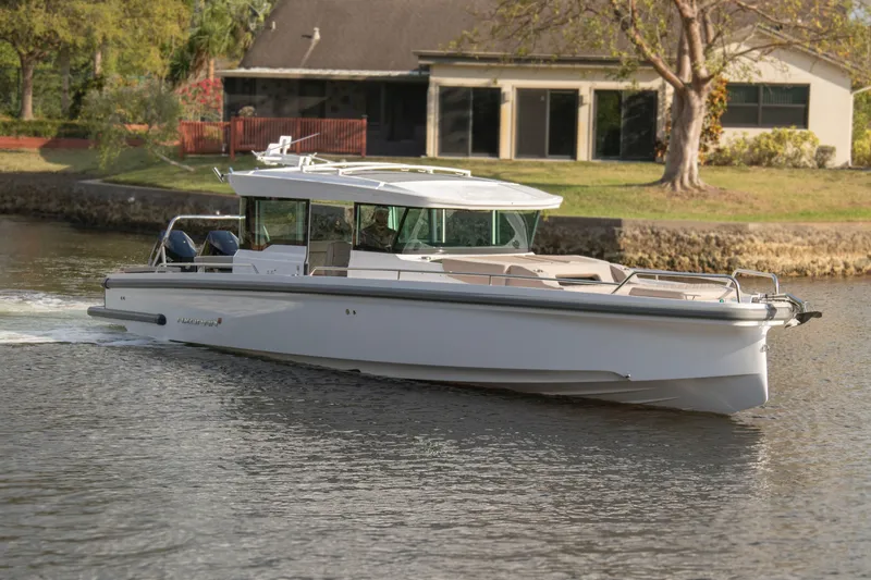 Slide: The Image of 2024 Axopar 37XC CROSS CABIN cruising on a calm river near a house. - 6