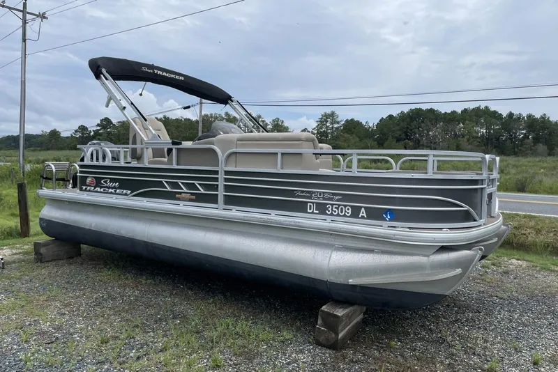 Slide: The Image of 2023 Sun Tracker Fishin' Barge 20 DLX pontoon boat on display outdoors. - 2