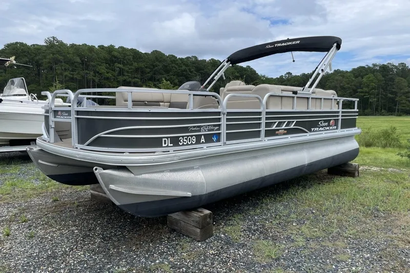 Slide: The Image of 2023 Sun Tracker Fishin' Barge 20 DLX pontoon boat on grassy area, overcast sky. - 4