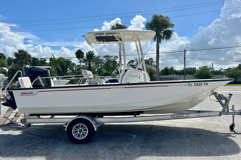 The Image of 2023 Boston Whaler 210 Montauk boat on trailer, parked outdoors under a clear sky. - 0
