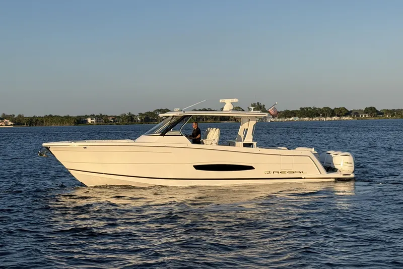 The Image of 2021 Regal 38 SAV boat cruising on calm water at sunset. - 0