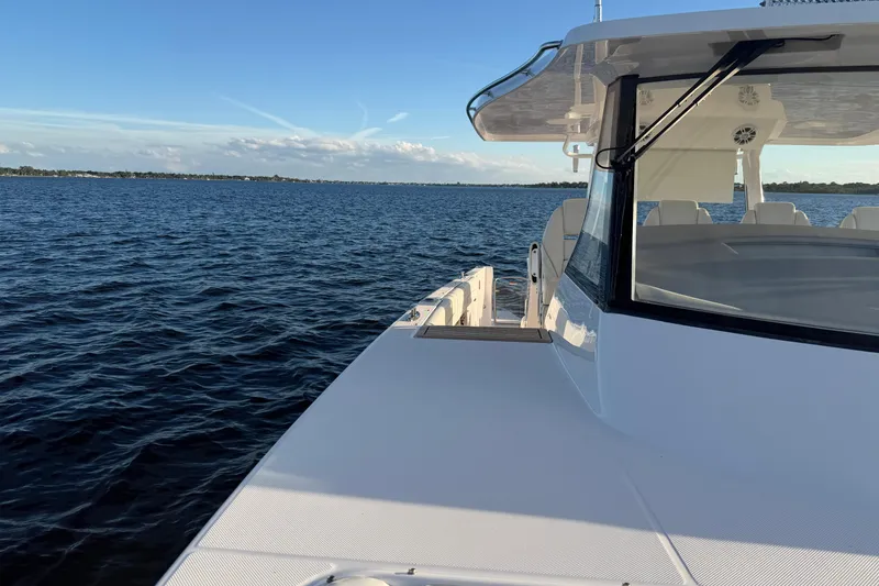 Slide: The Image of 2021 Regal 38 SAV yacht cruising on open water under clear blue skies. - 12