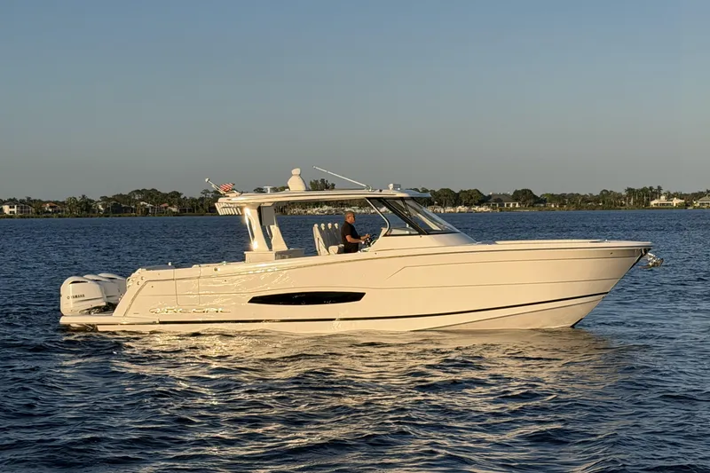 Slide: The Image of 2021 Regal 38 SAV boat cruising on a calm lake at sunset. - 2