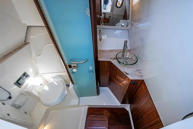 Slide: The Image of Luxurious bathroom in 2020 Pursuit DC 365 Dual Console boat, featuring modern fixtures and wood accents. - 26