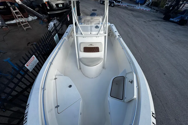Slide: The Image of 2021 Cobia 220 Center Console boat, white interior, docked in a marina setting. - 16