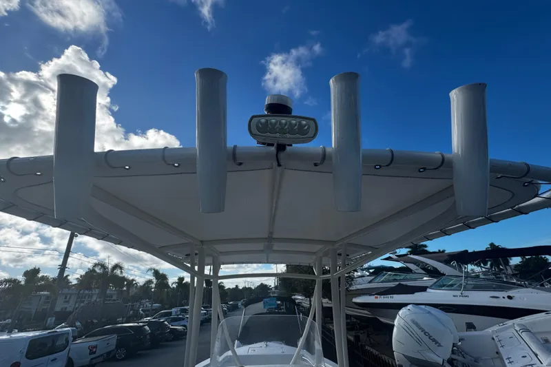Slide: The Image of 2021 Cobia 220 Center Console boat with T-top and rod holders under a blue sky. - 4