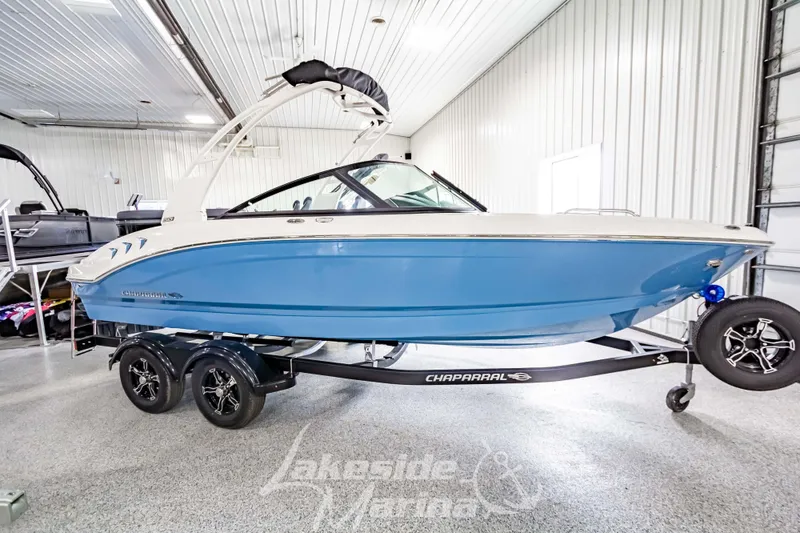The Image of 2026 Chaparral 21 SSi boat in showroom, blue hull, on trailer. - 1
