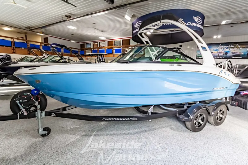 Slide: The Image of 2026 Chaparral 21 SSi boat in showroom, blue and white exterior, on trailer. - 9