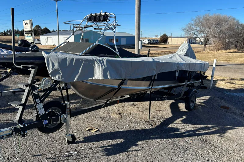 Slide: The Image of 2024 Lund 1600 Fury Tiller boat on trailer, covered, in outdoor setting. - 1