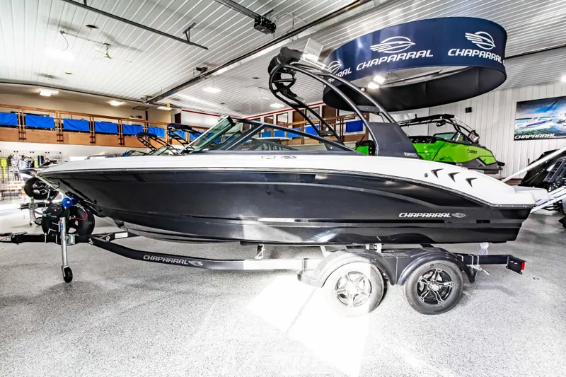 Slide: The Image of 2026 Chaparral 21 SSi boat in showroom, sleek black and white design. - 6