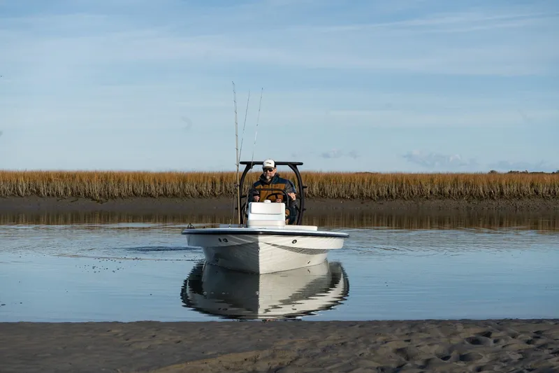 Slide: The Image of 2025 Chittum Skiffs 18 Islamorada navigating calm waters with marshland backdrop. - 6
