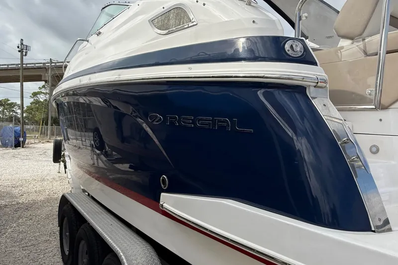 Slide: The Image of 2018 Regal 28 Express boat on trailer under a partly cloudy sky. - 2