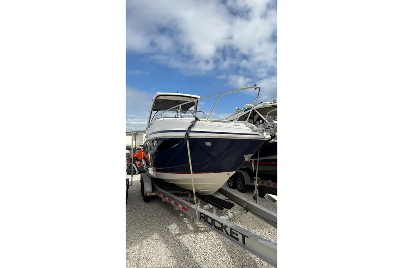 Slide: The Image of 2018 Regal 28 Express boat on trailer, blue and white exterior, parked outdoors. - 3