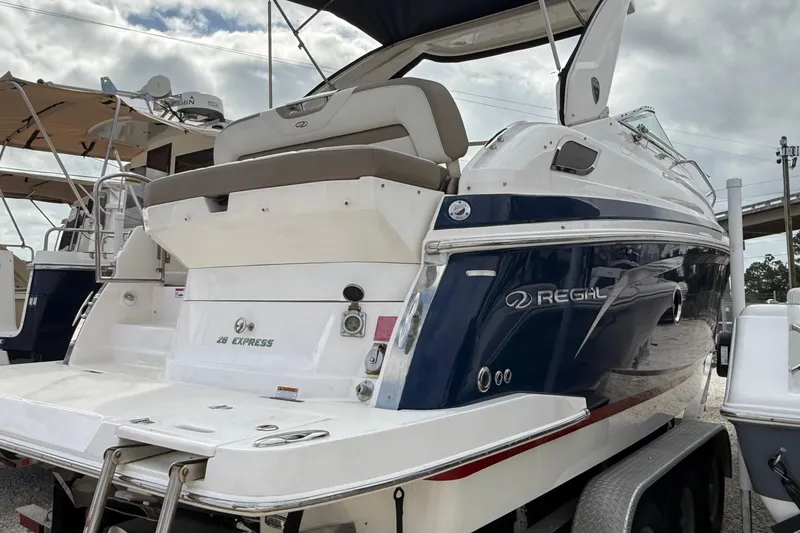 Slide: The Image of 2018 Regal 28 Express boat interior with seating and helm, parked outdoors. - 7