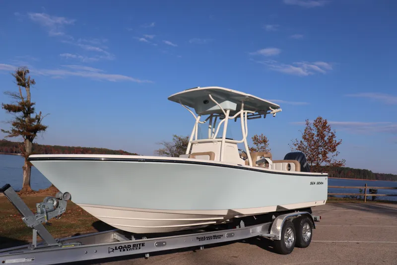 The Image of 2024 Sea Born LX24 Center Console boat on trailer by a lake. - 0