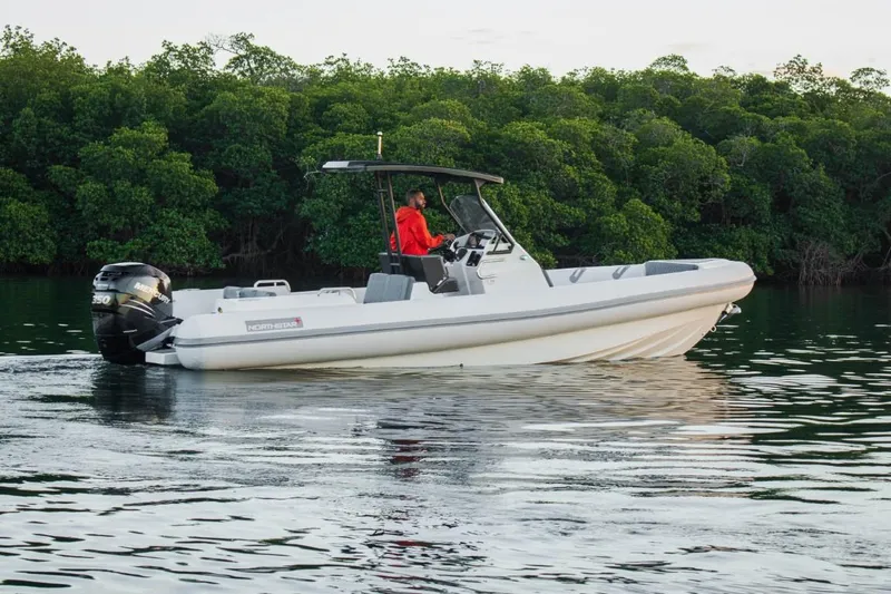 The Image of 2024 Northstar Orion 8 boat cruising on calm water near lush greenery. - 0