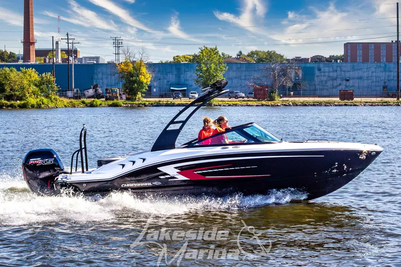 The Image of 2026 Chaparral 21 SSi OB boat cruising on a sunny day near industrial buildings. - 1