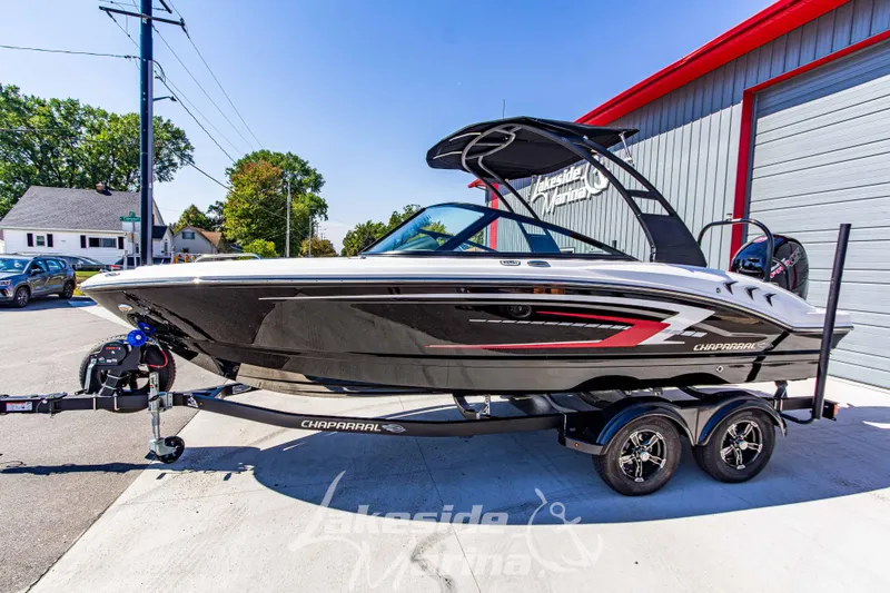 Slide: The Image of 2026 Chaparral 21 SSi OB boat on trailer, parked outside a marina. - 10