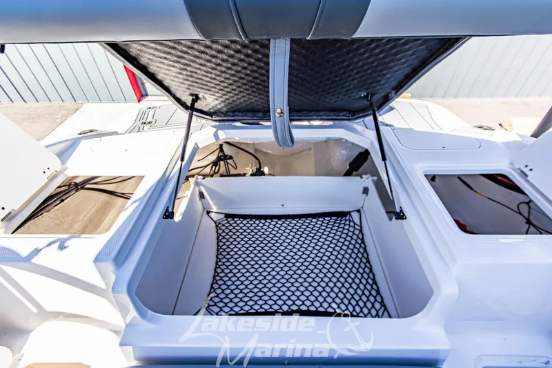Slide: The Image of 2026 Chaparral 21 SSi OB boat storage compartment with open hatch and netting. - 19