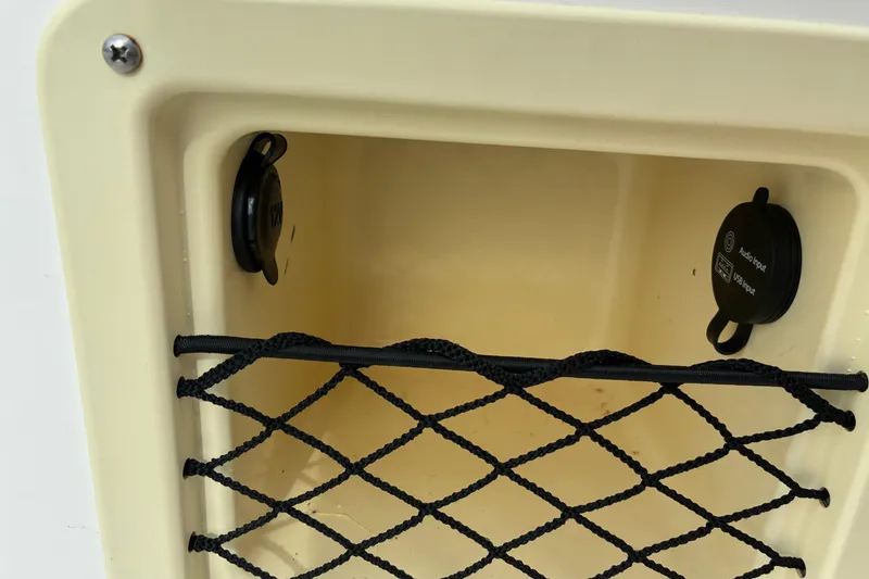 Slide: The Image of 2023 Bayliner Element 180 XL storage compartment with netting and input ports. - 13