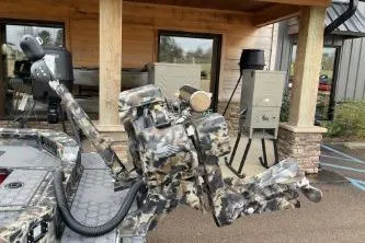 Slide: The Image of 2026 Excel 1751 Viper F4 boat with camouflage design, parked near a wooden building. - 5