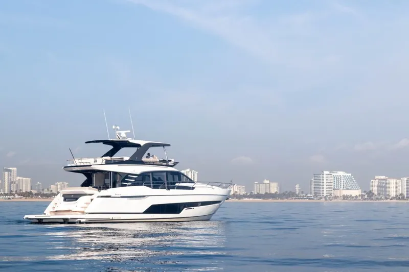 Slide: The Image of 2024 Fairline Squadron 68 yacht cruising near a coastal city skyline. - 3