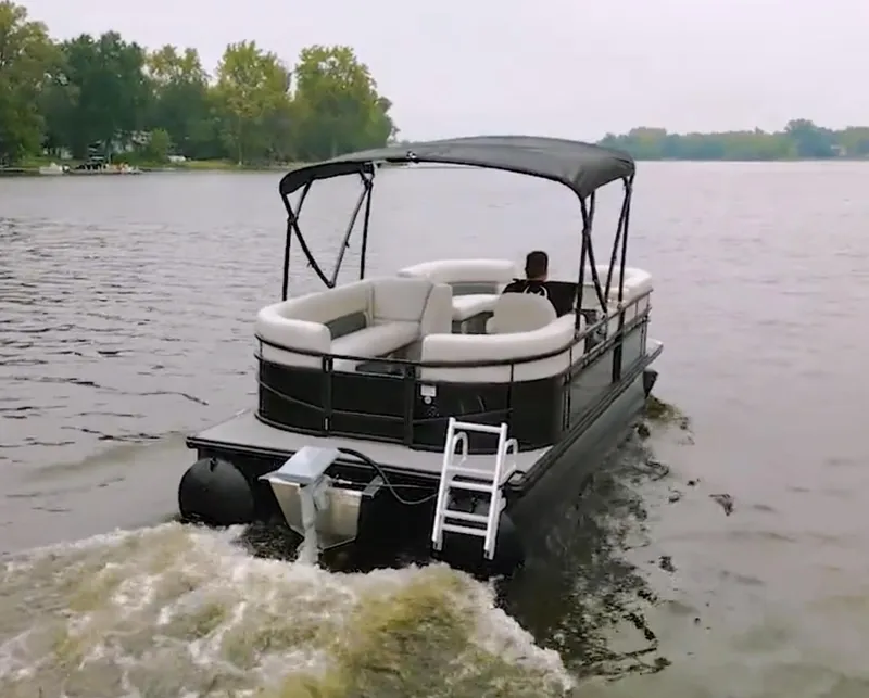 Slide: The Image of 2024 Vision Marine Technologies WX Tritoon cruising on a lake with lush green shoreline. - 6