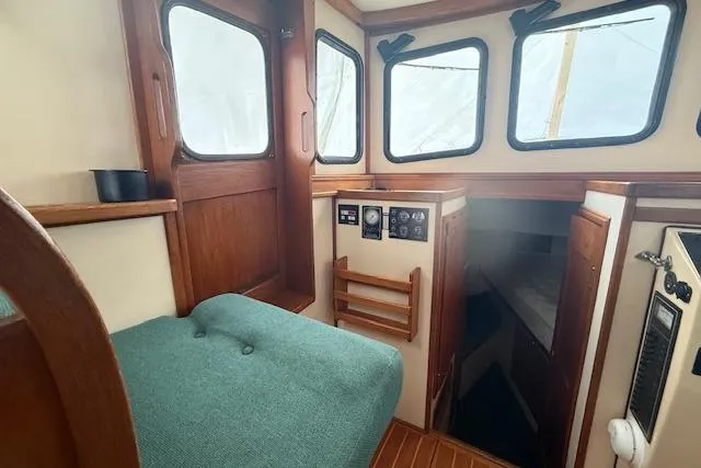 Slide: The Image of 1996 Nordic Tug 26 interior with wood paneling and green cushioned seating. - 10
